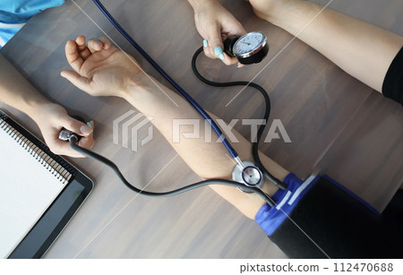Doctor measuring blood pressure with tonometer at table in clinic closeup 112470688