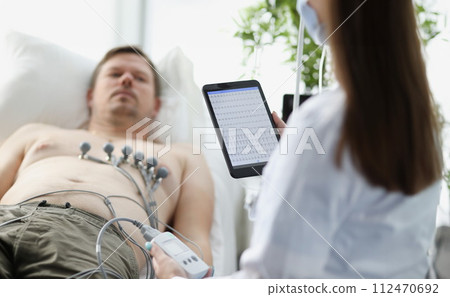 Doctor taking cardiogram to patient on couch in clinic closeup 112470692
