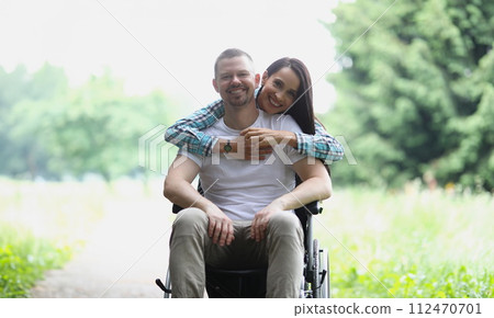 Woman hugging man in wheelchair in park portrait Woman hugging man in wheelchair in park portrait 112470701