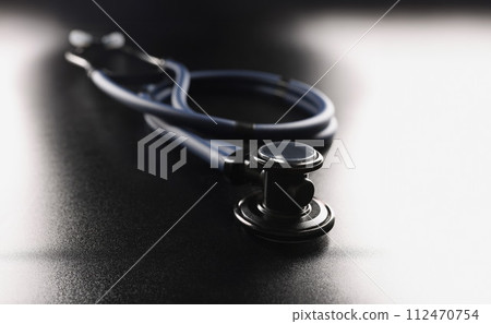 Dark blue stethoscope lying on black background closeup 112470754