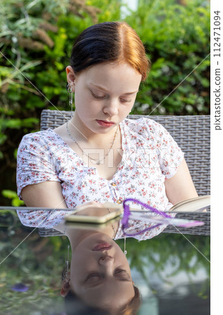 Young Woman Engrossed in a Good Book Outdoors 112471094