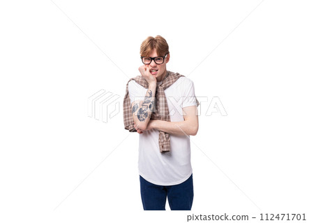 young pensive european red-haired guy in a t-shirt and shirt tied on his shoulders young pensive european red-haired guy in a t-shirt and shirt tied on his shoulders 112471701