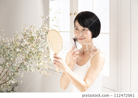 美容：靠窗照鏡子並使用臉部美容儀的女人 112472061