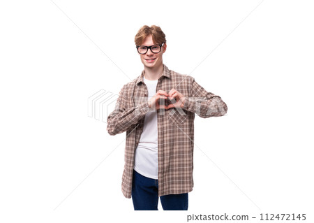 handsome red-haired caucasian student guy in glasses dressed in a plaid shirt shows a heart handsome red-haired caucasian student guy in glasses dressed in a plaid shirt shows a heart 112472145