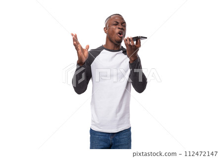 a young well-groomed African guy dressed in a black-and-white sweatshirt and jeans speaks on the a young well-groomed African guy dressed in a black-and-white sweatshirt and jeans speaks on the 112472147