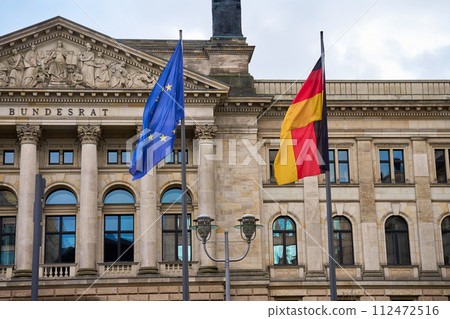 National flag of Germany and flag of the European Union are fluttering in the wind against background of Bundestag building. Government building in Berlin 112472516