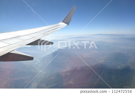 plane wing and mountain of China on sky through window frame 112472558