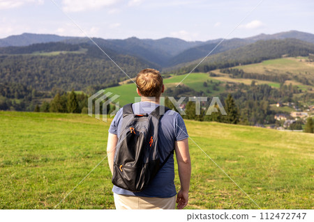 Young male with backpack hiking in nature. Back view. Travel and active lifestyle concept, outdoor activities 112472747
