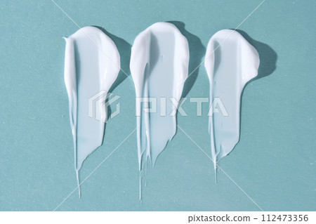 Three strokes of white cream on a blue background. 112473356