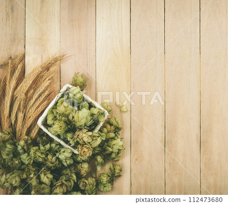 Fresh green hops on a wooden background. Green hop cones on wood. 112473680