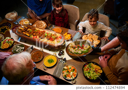 In this captivating aerial view, delicious food adorned with Ramadan decorations, including dates and meat, awaits the arrival of an European Islamic family, promising a festive and flavorful iftar In this captivating aerial view, delicious food adorned with Ramadan decorations, including dates and meat, awaits the arrival of an European Islamic family, promising a festive and flavorful iftar 112474894