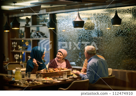A modern and traditional European Islamic family comes together for iftar in a contemporary restaurant during the Ramadan fasting period, embodying cultural harmony and familial unity amidst a A modern and traditional European Islamic family comes together for iftar in a contemporary restaurant during the Ramadan fasting period, embodying cultural harmony and familial unity amidst a 112474910