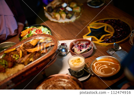 In this captivating aerial view, delicious food adorned with Ramadan decorations, including dates and meat, awaits the arrival of an European Islamic family, promising a festive and flavorful iftar 112474916