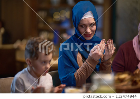 In a modern restaurant setting, a European Islamic family comes together for iftar during Ramadan, engaging in prayer before the meal, uniting tradition and contemporary practices in a celebration of In a modern restaurant setting, a European Islamic family comes together for iftar during Ramadan, engaging in prayer before the meal, uniting tradition and contemporary practices in a celebration of 112474944