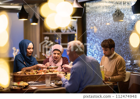 A modern and traditional European Islamic family comes together for iftar in a contemporary restaurant during the Ramadan fasting period, embodying cultural harmony and familial unity amidst a 112474948
