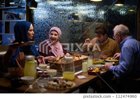 A modern and traditional European Islamic family comes together for iftar in a contemporary restaurant during the Ramadan fasting period, embodying cultural harmony and familial unity amidst a A modern and traditional European Islamic family comes together for iftar in a contemporary restaurant during the Ramadan fasting period, embodying cultural harmony and familial unity amidst a 112474960