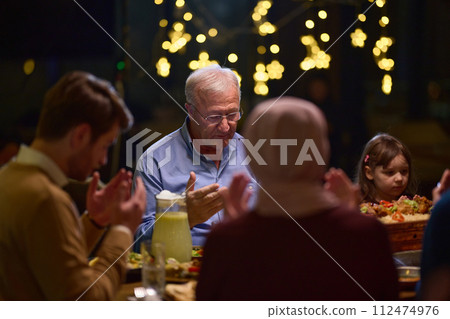 In a modern restaurant setting, a European Islamic family comes together for iftar during Ramadan, engaging in prayer before the meal, uniting tradition and contemporary practices in a celebration of In a modern restaurant setting, a European Islamic family comes together for iftar during Ramadan, engaging in prayer before the meal, uniting tradition and contemporary practices in a celebration of 112474976