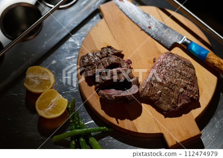 Close-up shot, a professional chef expertly prepares a delicious steak using modern cooking techniques, showcasing culinary excellence and precision in the art of gourmet cuisine 112474979