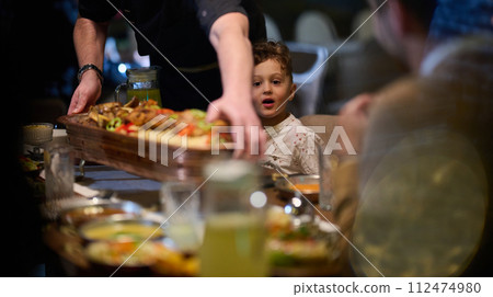 In a heartwarming scene, a professional chef serves an European Muslim family their iftar meal during the holy month of Ramadan, embodying cultural unity and culinary hospitality in a moment of shared In a heartwarming scene, a professional chef serves an European Muslim family their iftar meal during the holy month of Ramadan, embodying cultural unity and culinary hospitality in a moment of shared 112474980