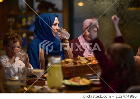 A modern and traditional European Islamic family comes together for iftar in a contemporary restaurant during the Ramadan fasting period, embodying cultural harmony and familial unity amidst a A modern and traditional European Islamic family comes together for iftar in a contemporary restaurant during the Ramadan fasting period, embodying cultural harmony and familial unity amidst a 112474986