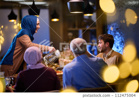 A modern and traditional European Islamic family comes together for iftar in a contemporary restaurant during the Ramadan fasting period, embodying cultural harmony and familial unity amidst a A modern and traditional European Islamic family comes together for iftar in a contemporary restaurant during the Ramadan fasting period, embodying cultural harmony and familial unity amidst a 112475004