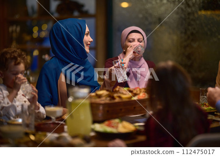 A modern and traditional European Islamic family comes together for iftar in a contemporary restaurant during the Ramadan fasting period, embodying cultural harmony and familial unity amidst a A modern and traditional European Islamic family comes together for iftar in a contemporary restaurant during the Ramadan fasting period, embodying cultural harmony and familial unity amidst a 112475017