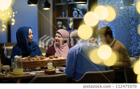 A modern and traditional European Islamic family comes together for iftar in a contemporary restaurant during the Ramadan fasting period, embodying cultural harmony and familial unity amidst a A modern and traditional European Islamic family comes together for iftar in a contemporary restaurant during the Ramadan fasting period, embodying cultural harmony and familial unity amidst a 112475070