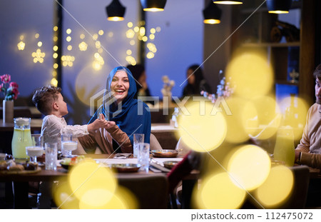 In a modern restaurant, an Islamic couple and their children joyfully await their iftar meal during the holy month of Ramadan, embodying familial harmony and cultural celebration amidst the In a modern restaurant, an Islamic couple and their children joyfully await their iftar meal during the holy month of Ramadan, embodying familial harmony and cultural celebration amidst the 112475072