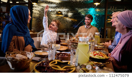 A modern and traditional European Islamic family comes together for iftar in a contemporary restaurant during the Ramadan fasting period, embodying cultural harmony and familial unity amidst a A modern and traditional European Islamic family comes together for iftar in a contemporary restaurant during the Ramadan fasting period, embodying cultural harmony and familial unity amidst a 112475079