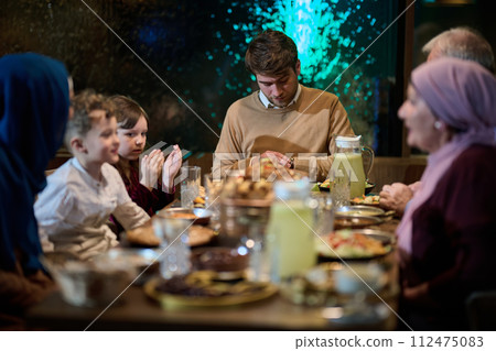 A modern and traditional European Islamic family comes together for iftar in a contemporary restaurant during the Ramadan fasting period, embodying cultural harmony and familial unity amidst a A modern and traditional European Islamic family comes together for iftar in a contemporary restaurant during the Ramadan fasting period, embodying cultural harmony and familial unity amidst a 112475083