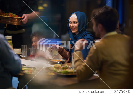 In a heartwarming scene, a professional chef serves an European Muslim family their iftar meal during the holy month of Ramadan, embodying cultural unity and culinary hospitality in a moment of shared 112475088