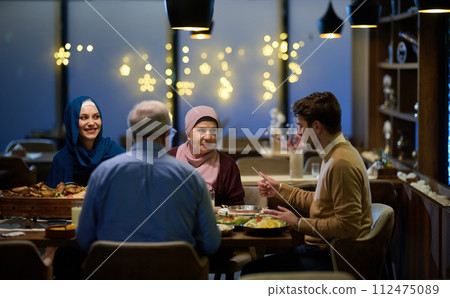 A modern and traditional European Islamic family comes together for iftar in a contemporary restaurant during the Ramadan fasting period, embodying cultural harmony and familial unity amidst a A modern and traditional European Islamic family comes together for iftar in a contemporary restaurant during the Ramadan fasting period, embodying cultural harmony and familial unity amidst a 112475089