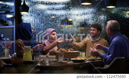 A modern and traditional European Islamic family comes together for iftar in a contemporary restaurant during the Ramadan fasting period, embodying cultural harmony and familial unity amidst a A modern and traditional European Islamic family comes together for iftar in a contemporary restaurant during the Ramadan fasting period, embodying cultural harmony and familial unity amidst a 112475095