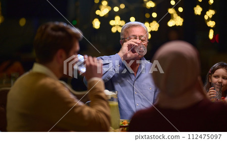 A modern and traditional European Islamic family comes together for iftar in a contemporary restaurant during the Ramadan fasting period, embodying cultural harmony and familial unity amidst a A modern and traditional European Islamic family comes together for iftar in a contemporary restaurant during the Ramadan fasting period, embodying cultural harmony and familial unity amidst a 112475097