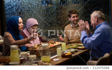 A modern and traditional European Islamic family comes together for iftar in a contemporary restaurant during the Ramadan fasting period, embodying cultural harmony and familial unity amidst a A modern and traditional European Islamic family comes together for iftar in a contemporary restaurant during the Ramadan fasting period, embodying cultural harmony and familial unity amidst a 112475098