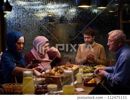 A modern and traditional European Islamic family comes together for iftar in a contemporary restaurant during the Ramadan fasting period, embodying cultural harmony and familial unity amidst a A modern and traditional European Islamic family comes together for iftar in a contemporary restaurant during the Ramadan fasting period, embodying cultural harmony and familial unity amidst a 112475131
