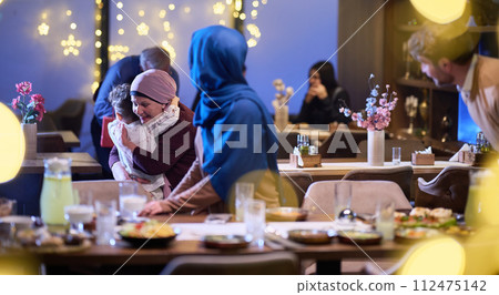Grandparents arrive at their children's and grandchildren's gathering for iftar in a restaurant during the holy month of Ramadan, bearing gifts and sharing cherished moments of love, unity, and 112475142
