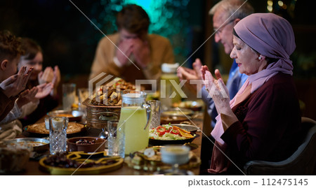 In a modern restaurant setting, a European Islamic family comes together for iftar during Ramadan, engaging in prayer before the meal, uniting tradition and contemporary practices in a celebration of In a modern restaurant setting, a European Islamic family comes together for iftar during Ramadan, engaging in prayer before the meal, uniting tradition and contemporary practices in a celebration of 112475145