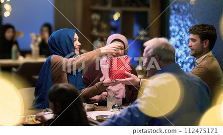 Grandparents arrive at their children's and grandchildren's gathering for iftar in a restaurant during the holy month of Ramadan, bearing gifts and sharing cherished moments of love, unity, and 112475171