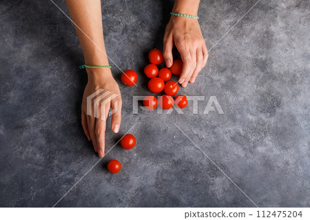 Woman holding ripe tomatoes cherry in her hands at gray table background, close up 112475204