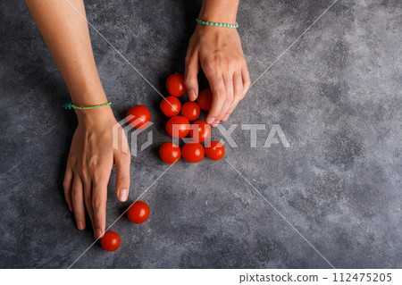 Woman holding ripe tomatoes cherry in her hands at gray table background, close up 112475205