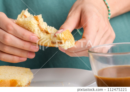 Female hands holding a bitten peanut butter sandwich with honey of wheat bread, have a breakfast 112475221