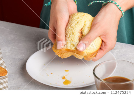 woman hands breaking a sandwich with honey and peanut butter of wheat bread on white plate 112475234
