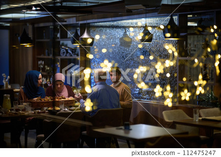 A modern and traditional European Islamic family comes together for iftar in a contemporary restaurant during the Ramadan fasting period, embodying cultural harmony and familial unity amidst a 112475247