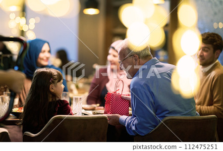 A modern and traditional European Islamic family comes together for iftar in a contemporary restaurant during the Ramadan fasting period, embodying cultural harmony and familial unity amidst a 112475251
