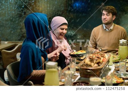 A modern and traditional European Islamic family comes together for iftar in a contemporary restaurant during the Ramadan fasting period, embodying cultural harmony and familial unity amidst a A modern and traditional European Islamic family comes together for iftar in a contemporary restaurant during the Ramadan fasting period, embodying cultural harmony and familial unity amidst a 112475258