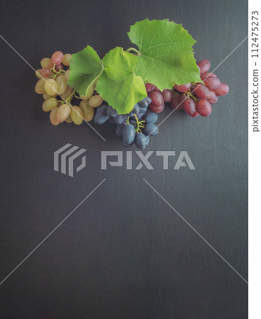 Bunches of grapes on old table and. Variety of ripe colorful grapes as the symbol of autumn Bunches of grapes on old table and. Variety of ripe colorful grapes as the symbol of autumn 112475273