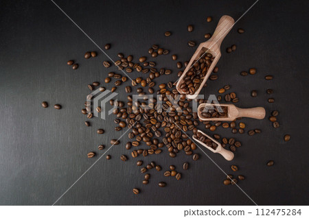 spoon with coffee on a black background.  spoon with coffee beans. Texture  of roasted coffee beans 112475284
