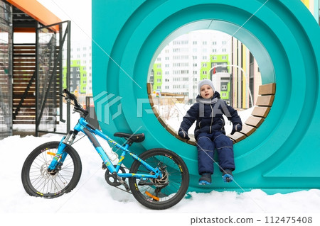 Little boy in snowsuit riding a bicycle 112475408