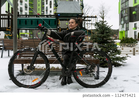 Sports concept, a young woman rented a bicycle and rides it along the city street Sports concept, a young woman rented a bicycle and rides it along the city street 112475421